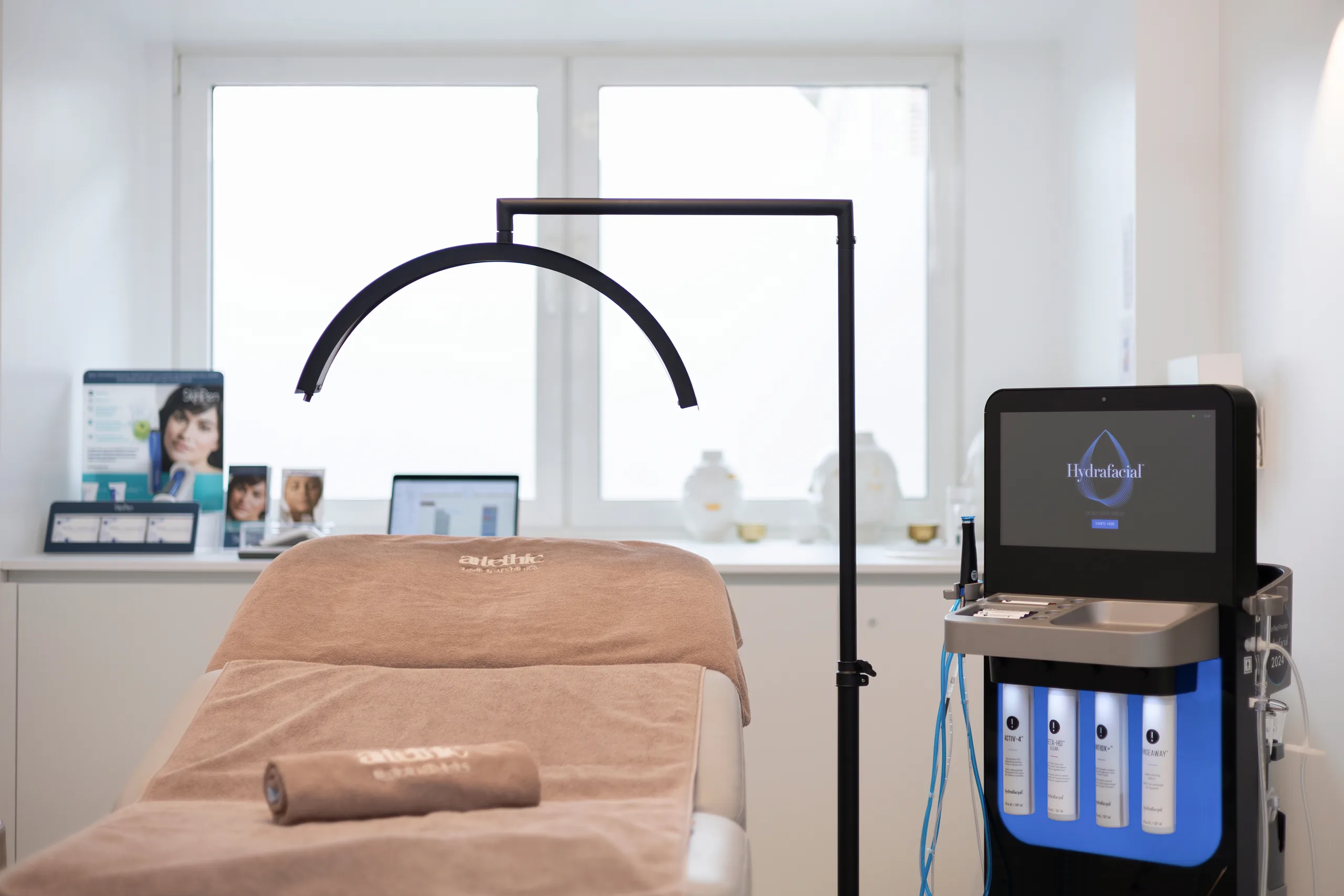 Beauty treatment room at the artethic® practice in Düsseldorf with a treatment couch, a magnifying lamp and a device for skin treatments.