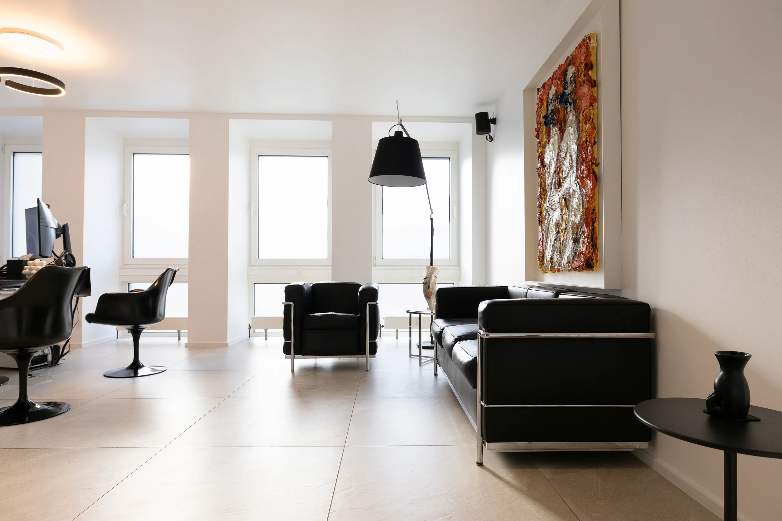 Beratungszimmer der Praxis artethic® in Düsseldorf mit schwarzen Ledersesseln und Bogenleuchte.